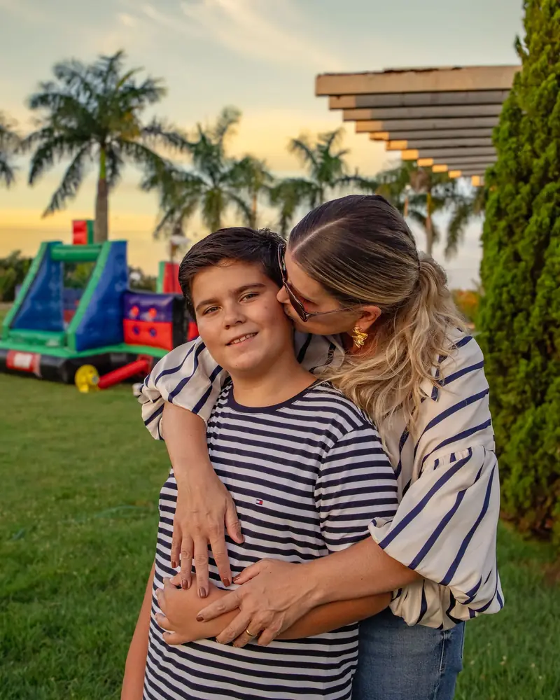 Mãe abraçando e beijando o filho em uma festa de família ao ar livre